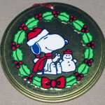 Snoopy sitting in wreath with snowman Round Metal Ornament