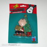Charlie Brown sitting next to Christmas Tree Ornament