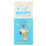 Vintage Peanuts plastic keychain featuring Snoopy warmly hugging Woodstock, still in its original light blue backing card titled "SNOOPY KEY CHAINS" in bold yellow and blue typography.