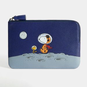 Astronaut Snoopy Anya Hindmarch leather coin purse featuring a dark blue night sky with a white moon above a lighter blue lunar surface, where an embroidered Snoopy in an astronaut helmet and a yellow Woodstock look out at the craters