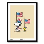 A framed art print on a light tan background featuring Snoopy wearing a star-patterned Uncle Sam top hat and red-and-white striped scarf while holding an American flag, standing facing Woodstock who wears a tiny patriotic hat and holds a matching small American flag.