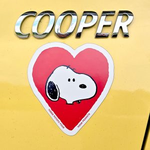 Snoopy heart sticker with the word "COOPER" in large metallic 3D bubble letters above a red heart-shaped sticker featuring Snoopy's face, with small text along the lower edge that reads "THREE POTATO FOUR" and copyright text for Peanuts