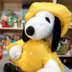 A Snoopy plush toy dressed in a bright yellow raincoat and matching yellow sou'wester hat.