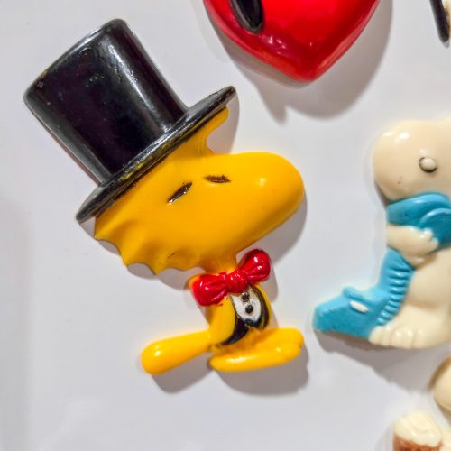 A vintage Woodstock magnet featuring Woodstock dressed in a black top hat and red bow tie, shown alongside other Peanuts magnets against a white background.