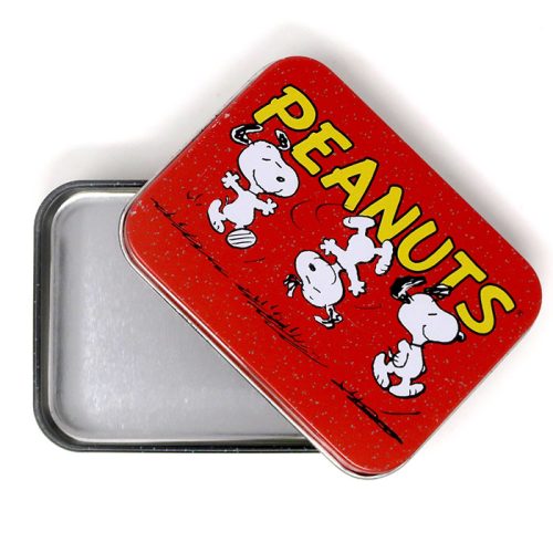 An open rectangular metal tin with a red lid featuring yellow "PEANUTS" lettering and illustrations of Snoopy dancing happily in multiple poses against a black speckled base.