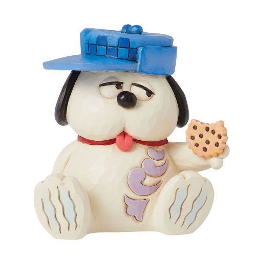 A Peanuts figurine of Olaf, Snoopy's brother, sitting down and wearing a large blue hat while holding out a chocolate chip cookie.